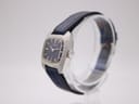 Side profile of Seiko ladies watch, showing brushed stainless steel cushion case and crown.