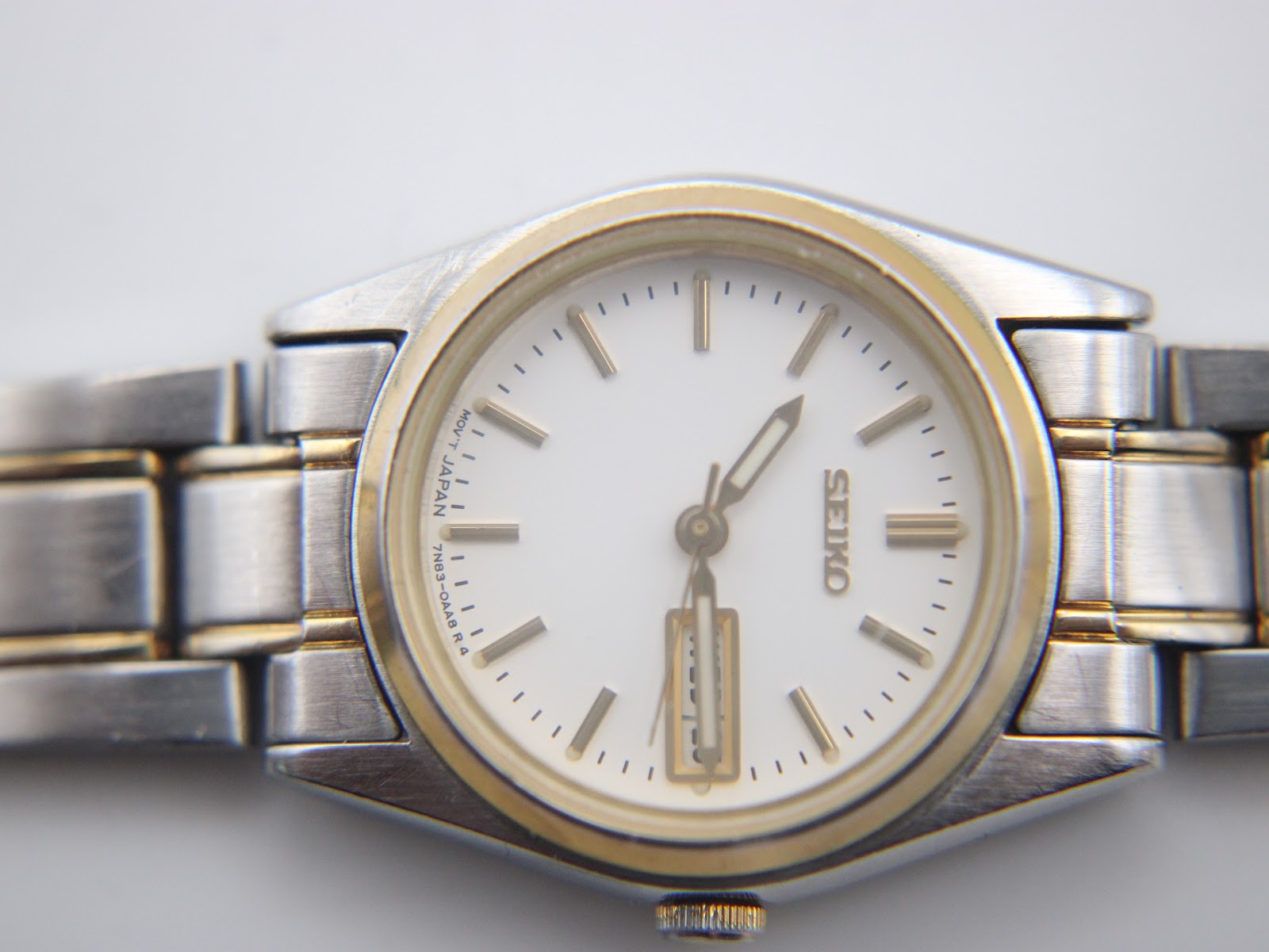Close-up of Seiko two-tone stainless steel bracelet with gold accents and signed clasp.
