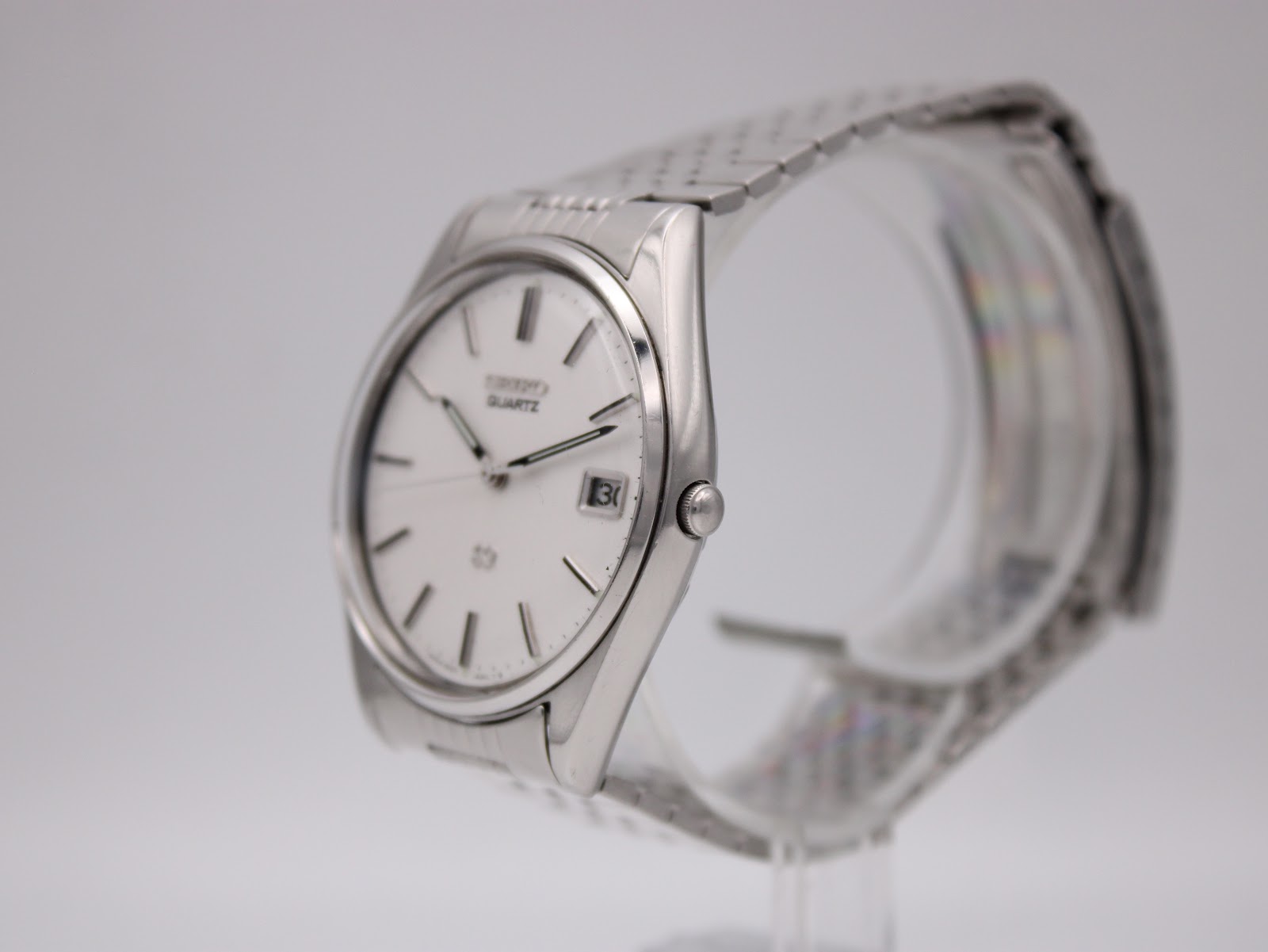 Angled view of the Seiko 8222-8020 watch, showing the silver stainless steel case, crown, and integrated bracelet.