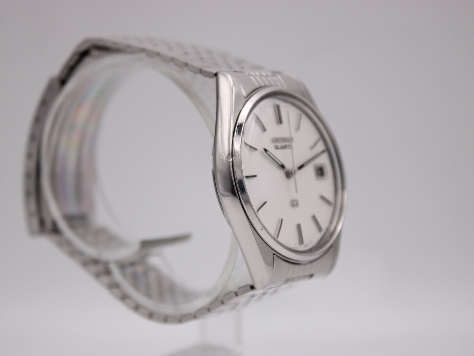 Side profile of the Seiko 8222-8020 watch, highlighting its slim case and integrated stainless steel bracelet on a display stand.