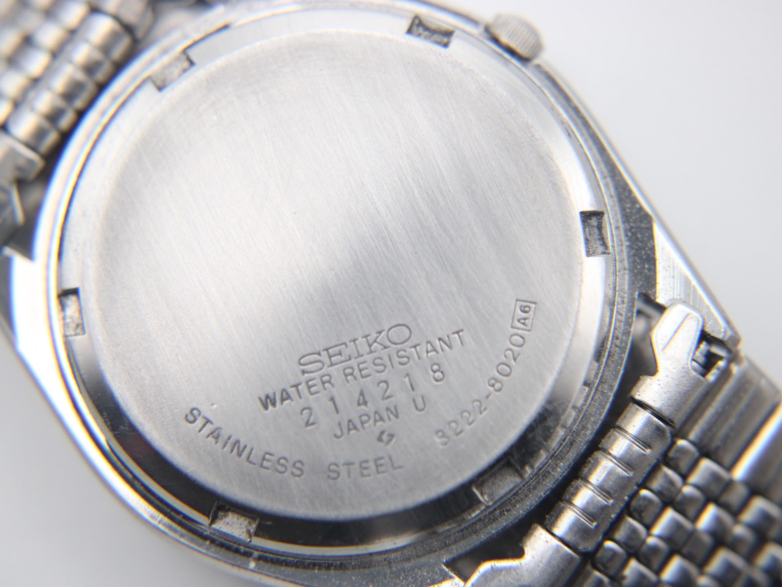 Close-up of the Seiko watch's stainless steel case back, showing "Seiko Water Resistant", serial number "214218", and model number "8222-8020".