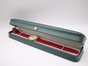 The Seiko watch with burgundy strap resting inside a green presentation box.
