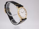 Left side profile view of the Seiko watch, showing the integrated lug design and black leather strap on a clear watch stand.