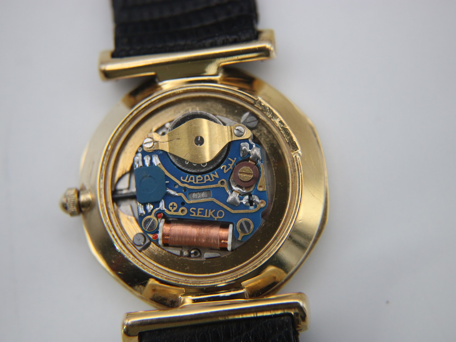 Close-up of the open case back revealing the Seiko quartz movement with 'Japan' text and copper coil.