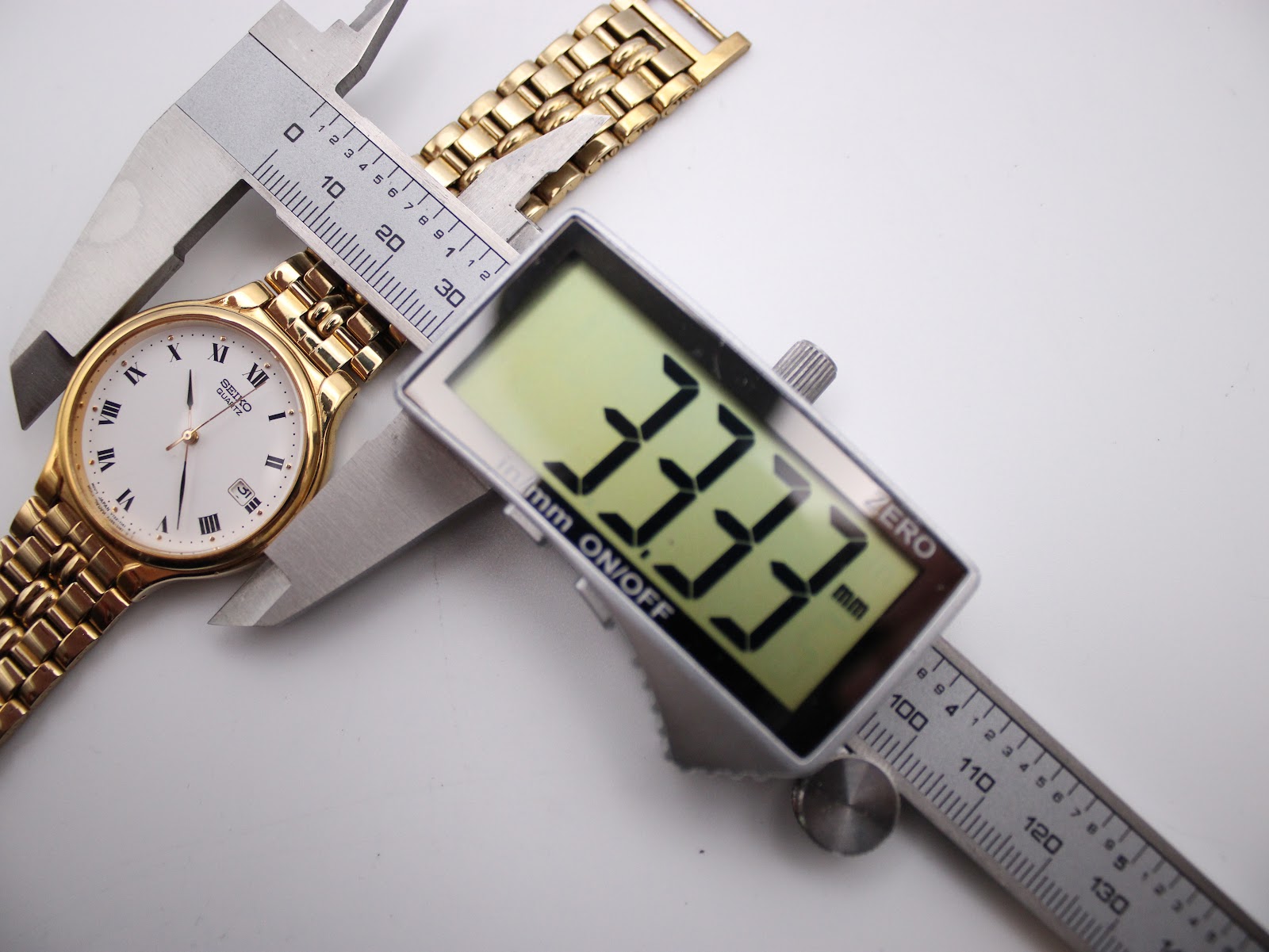 A digital caliper measuring the case diameter of the Seiko watch, showing a precise reading of 33.33mm.