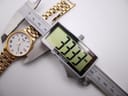 A digital caliper measuring the case diameter of the Seiko watch, showing a precise reading of 33.33mm.