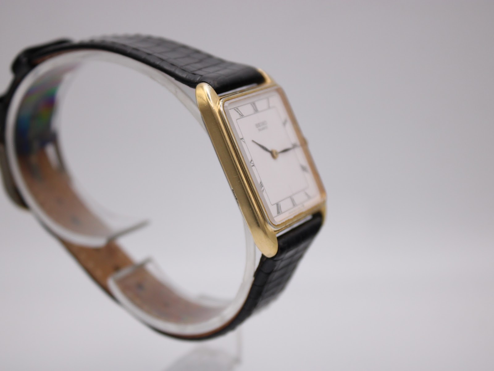 Close-up of the watch's black leather strap with crocodile pattern and gold-tone buckle.
