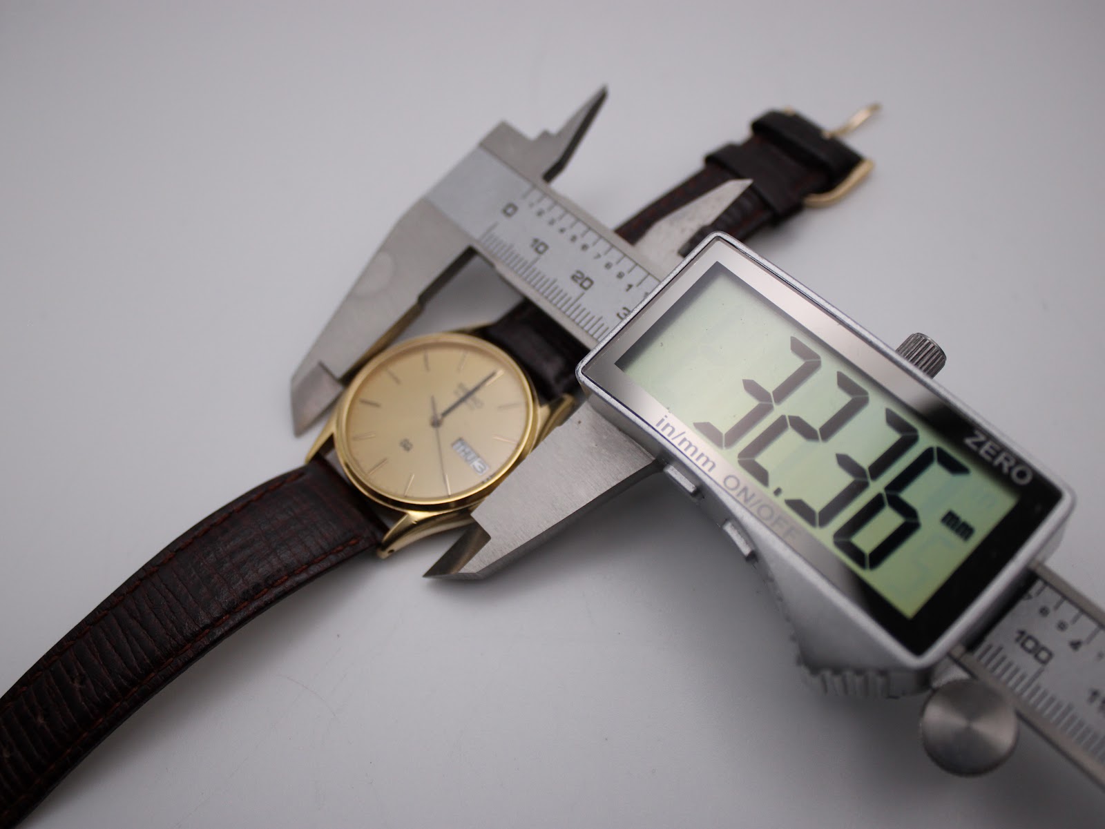 Digital caliper measuring the case diameter of the Seiko watch, showing a reading of 32.36mm.