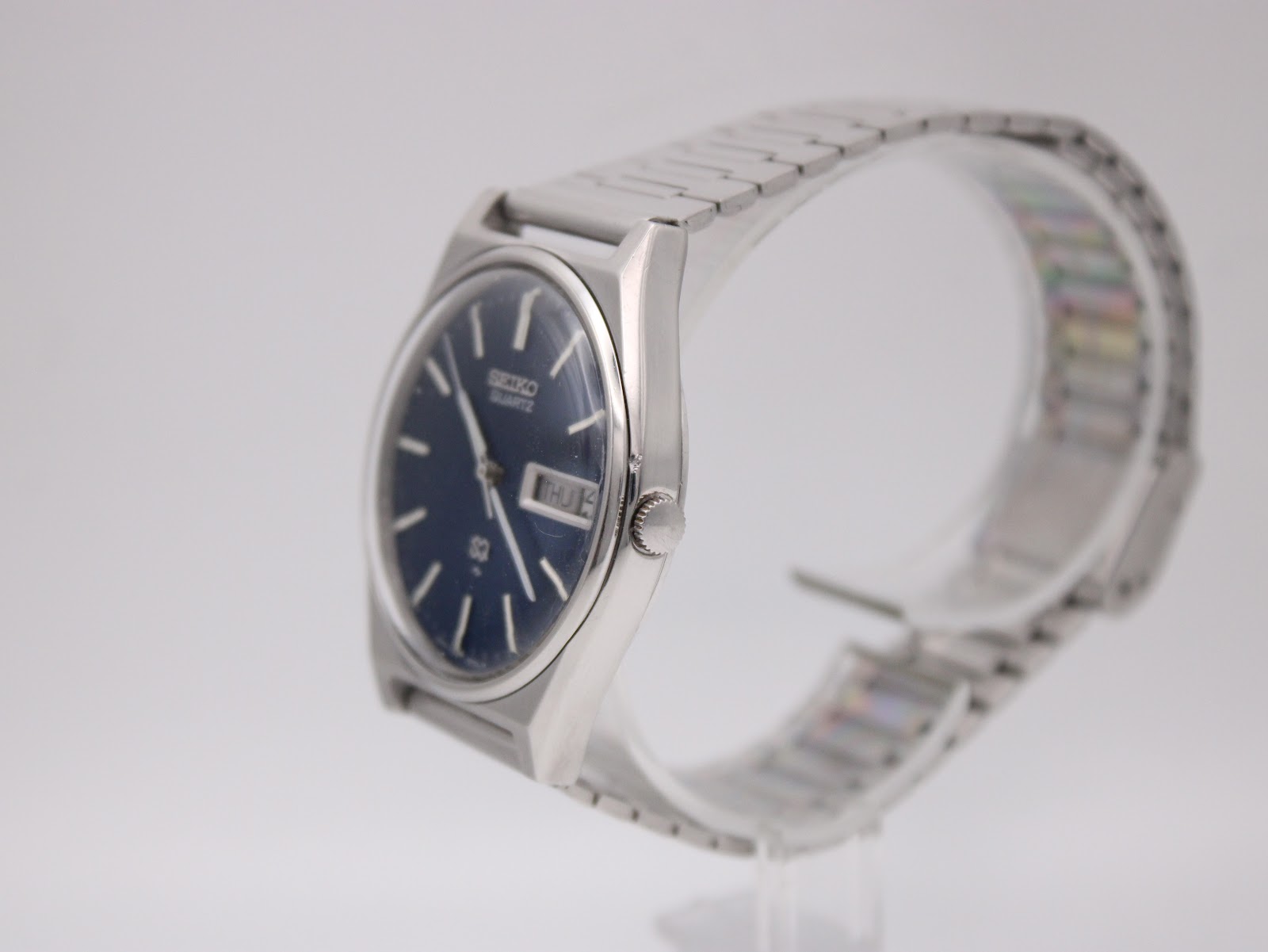 Side angled view of the Seiko 7123-8430 watch, highlighting its stainless steel case, crown, and integrated bracelet.