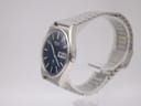 Side angled view of the Seiko 7123-8430 watch, highlighting its stainless steel case, crown, and integrated bracelet.