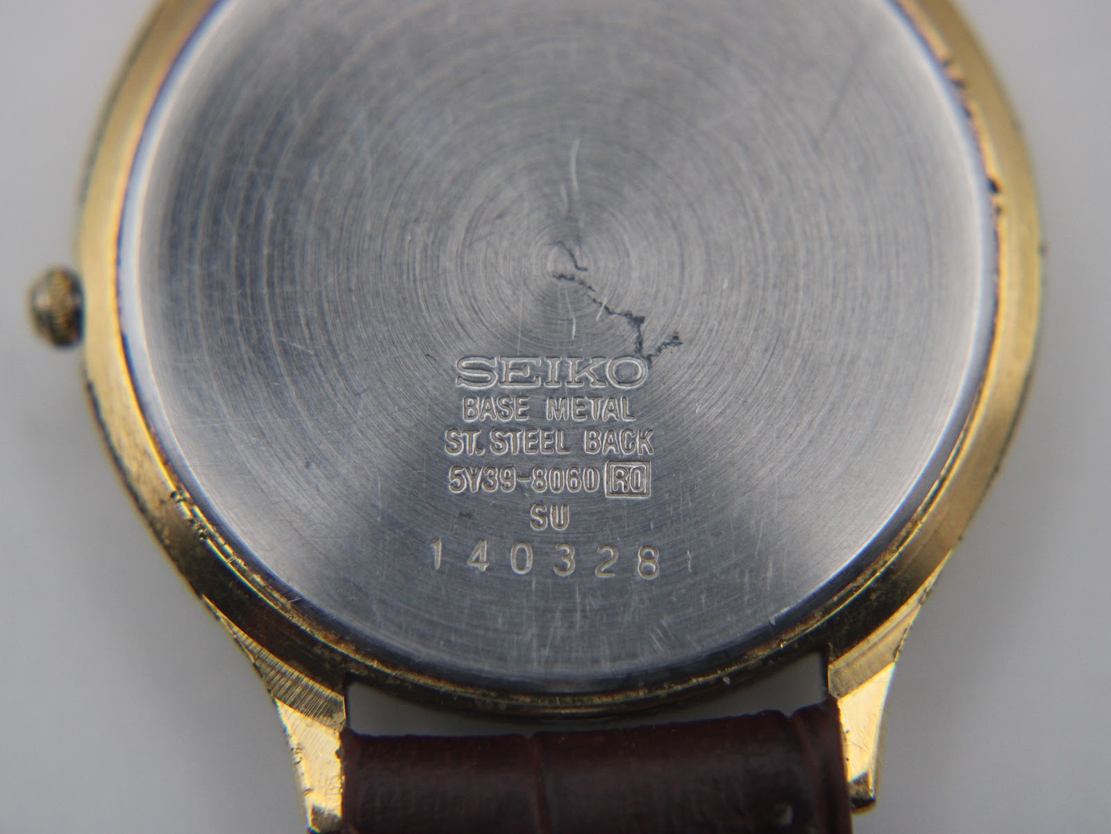 Close-up of the stainless steel case back, showing Seiko branding, model number 5Y39-8060, serial number 140328, and 'base metal' inscription.