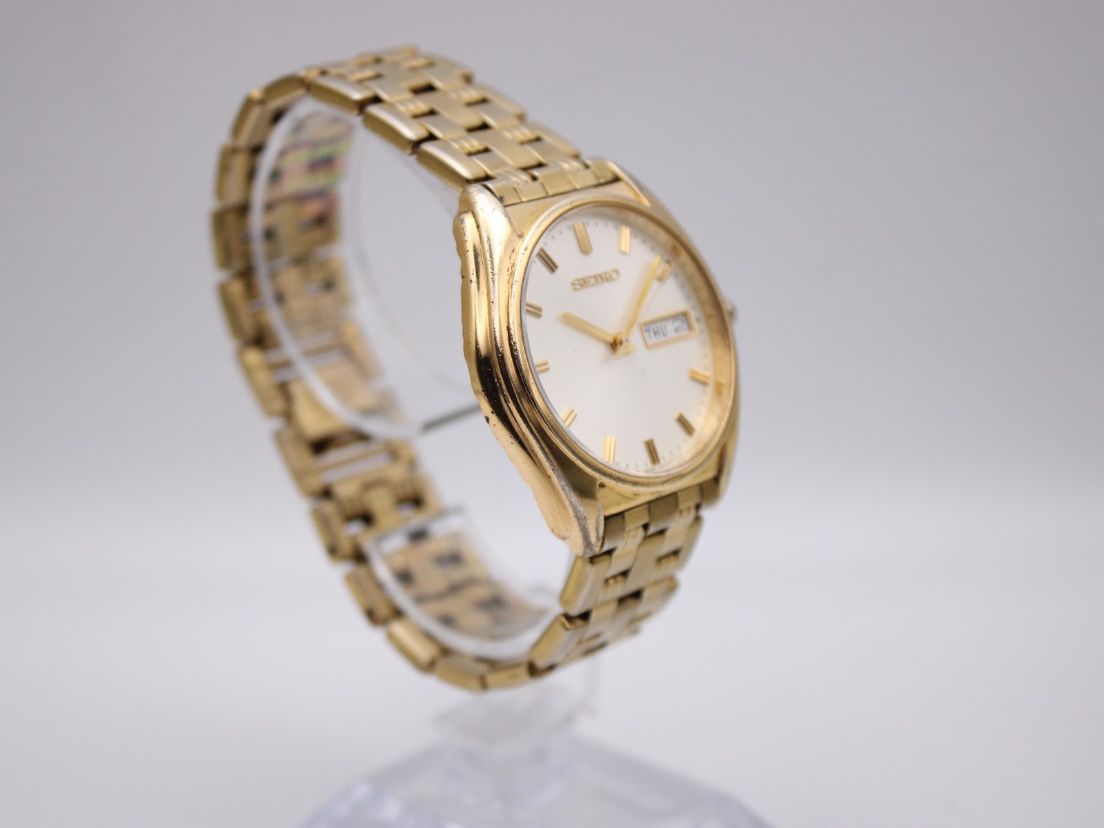 Another angled view of the gold-tone Seiko watch, highlighting the bracelet links and case wear.