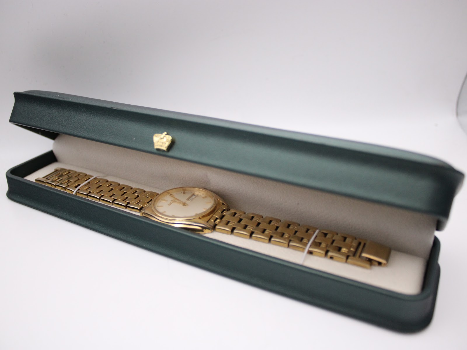 The pre-owned Seiko watch resting inside a generic green presentation box.