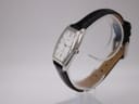 Side view of the Orient UNBH-CO watch on a stand, showing the curved profile of the polished silver-tone case and the black leather strap.