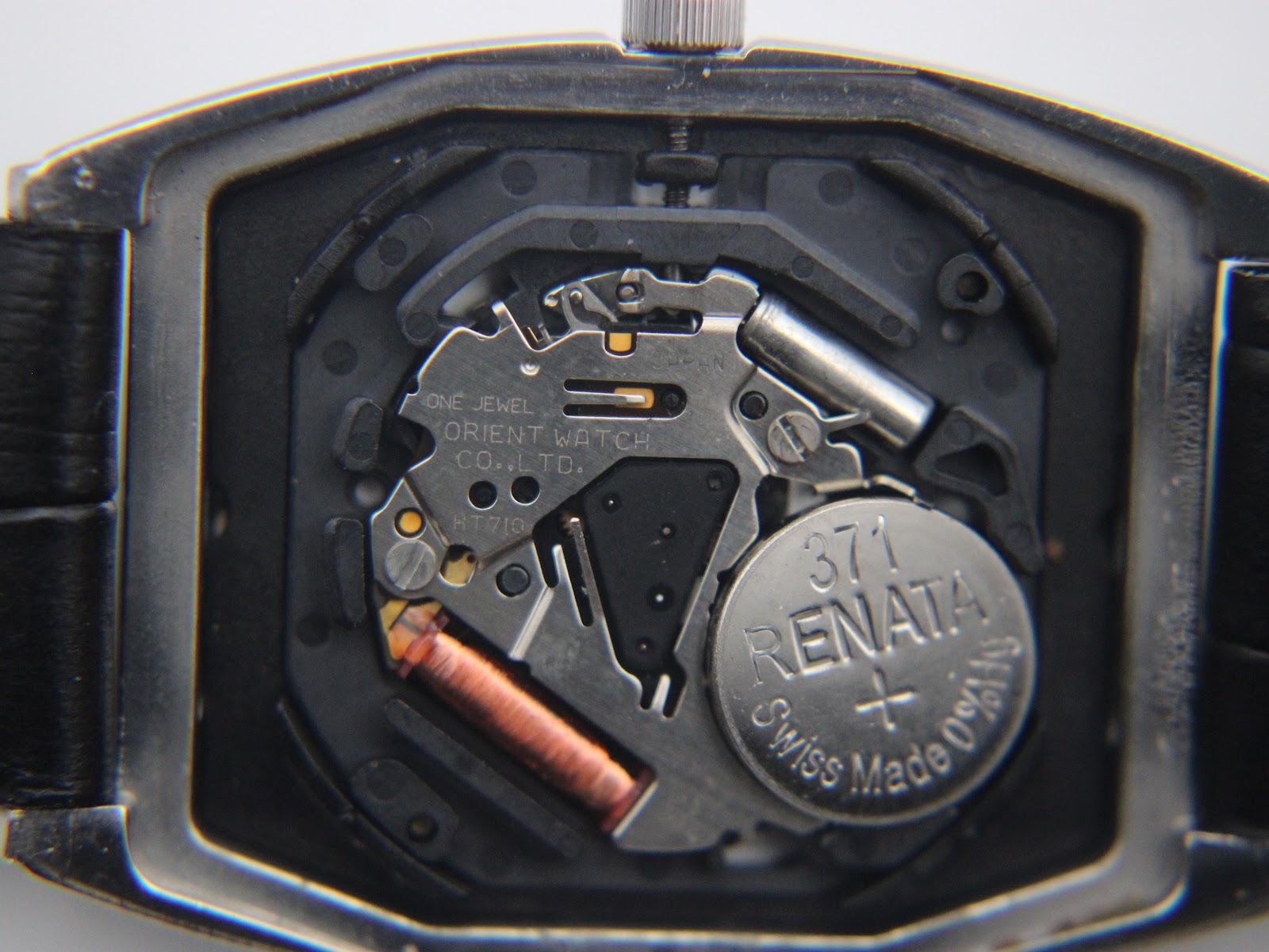 Close-up of the Orient quartz movement inside the watch, revealing the battery (Renata 371) and "One Jewel Orient Watch Co. Ltd." inscription.