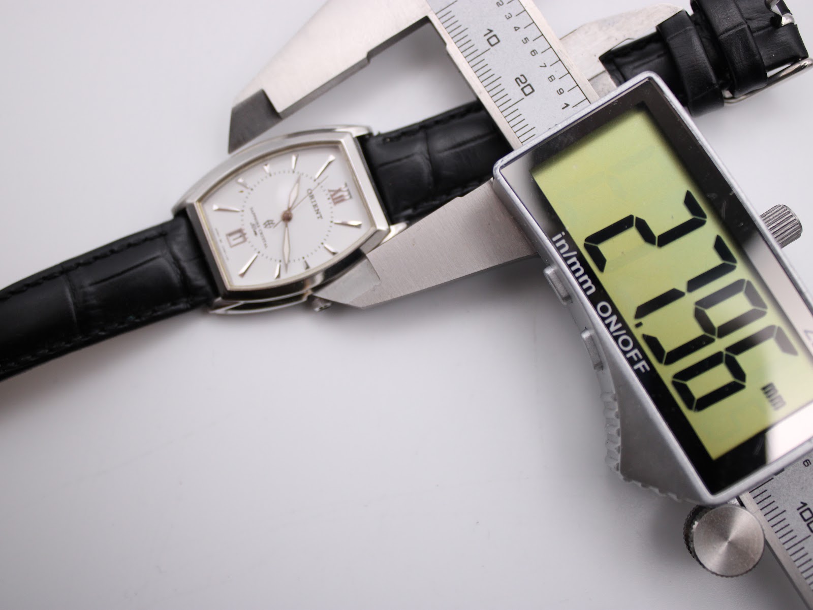 Digital caliper measuring the case width of the Orient UNBH-CO watch, displaying 27.06 mm.