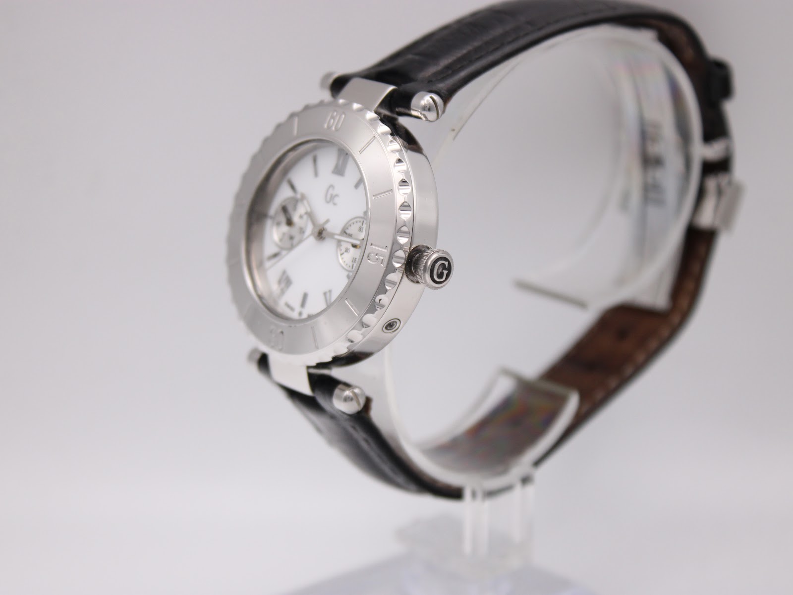 Side perspective view of the Gc watch on a stand, showing the crown and textured bezel.