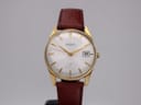 Front view of gold plated Seiko 6602-1990 with silver dial, gold baton indices, and brown leather strap on a display stand.