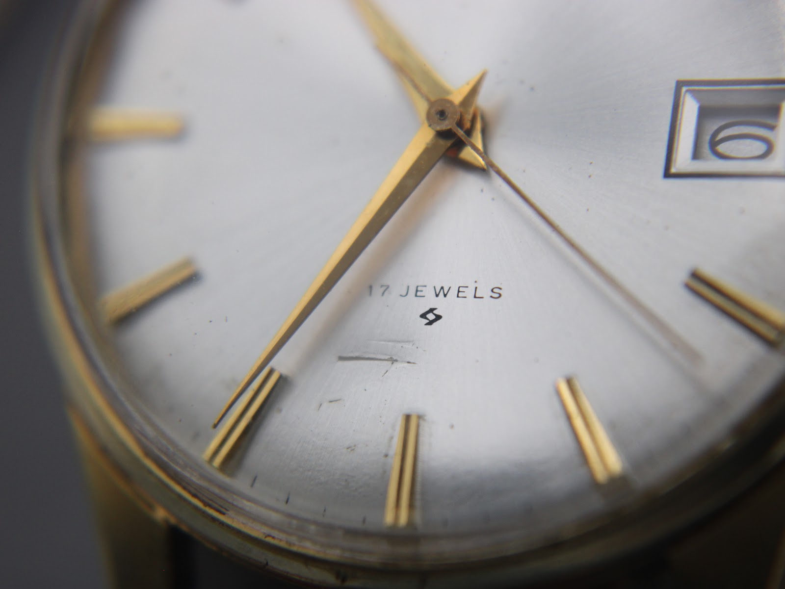 Macro close-up of the silver dial showing '17 JEWELS', the Seiko 'S' logo, and minor marks on the dial and crystal.
