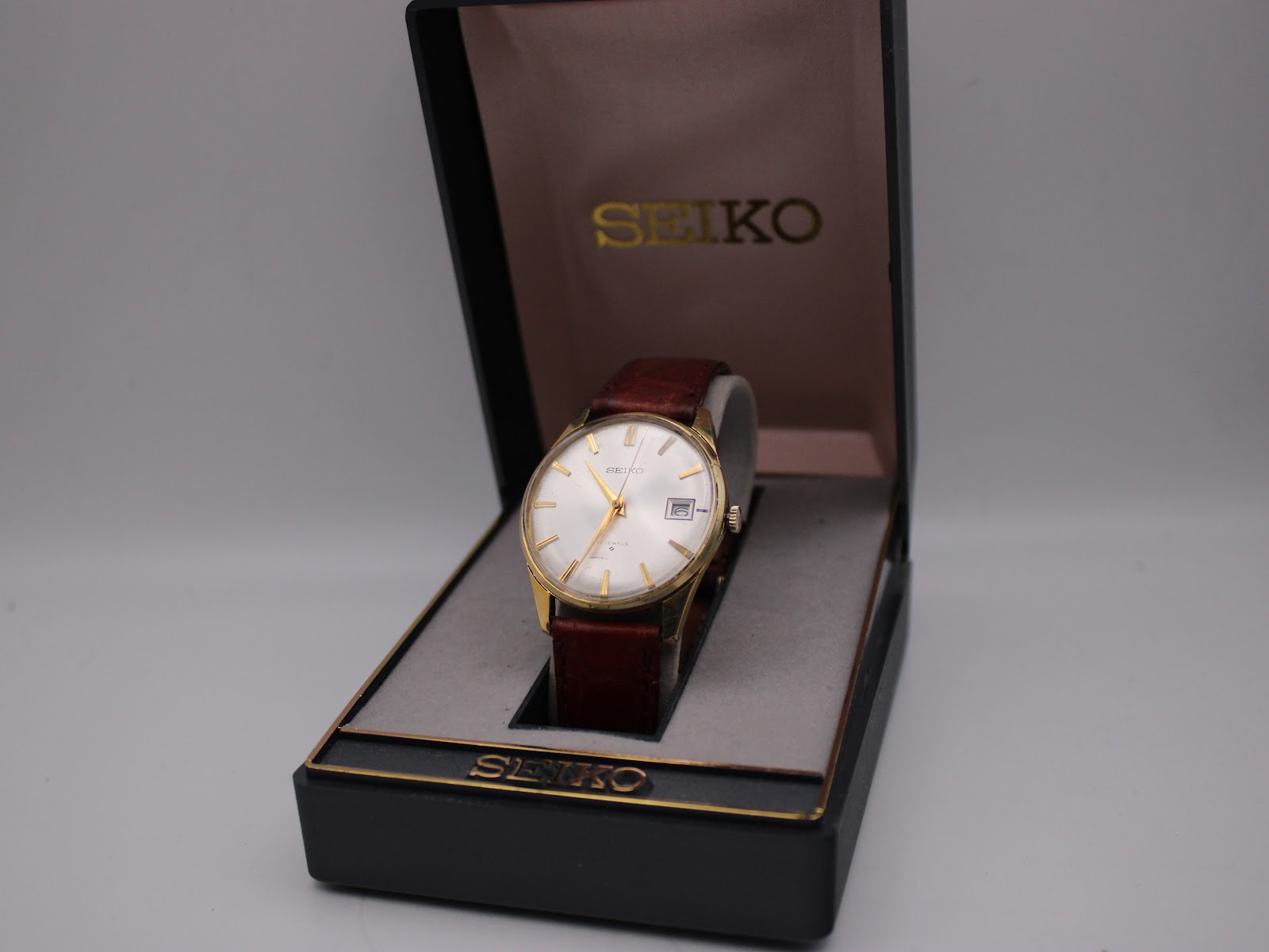 Front view of the Seiko watch displayed in its original black and gold Seiko box.