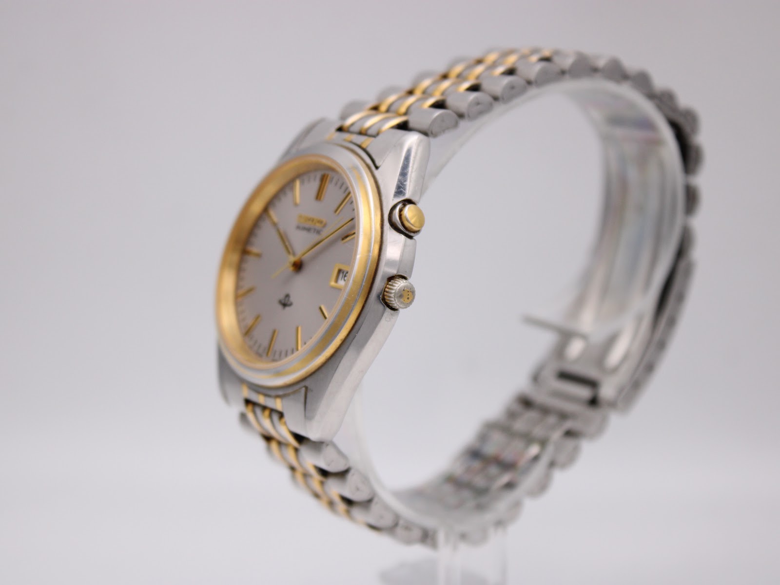 Right-side profile view of the Seiko Kinetic watch on a stand, showing the two-tone case, crown, and power reserve pusher.