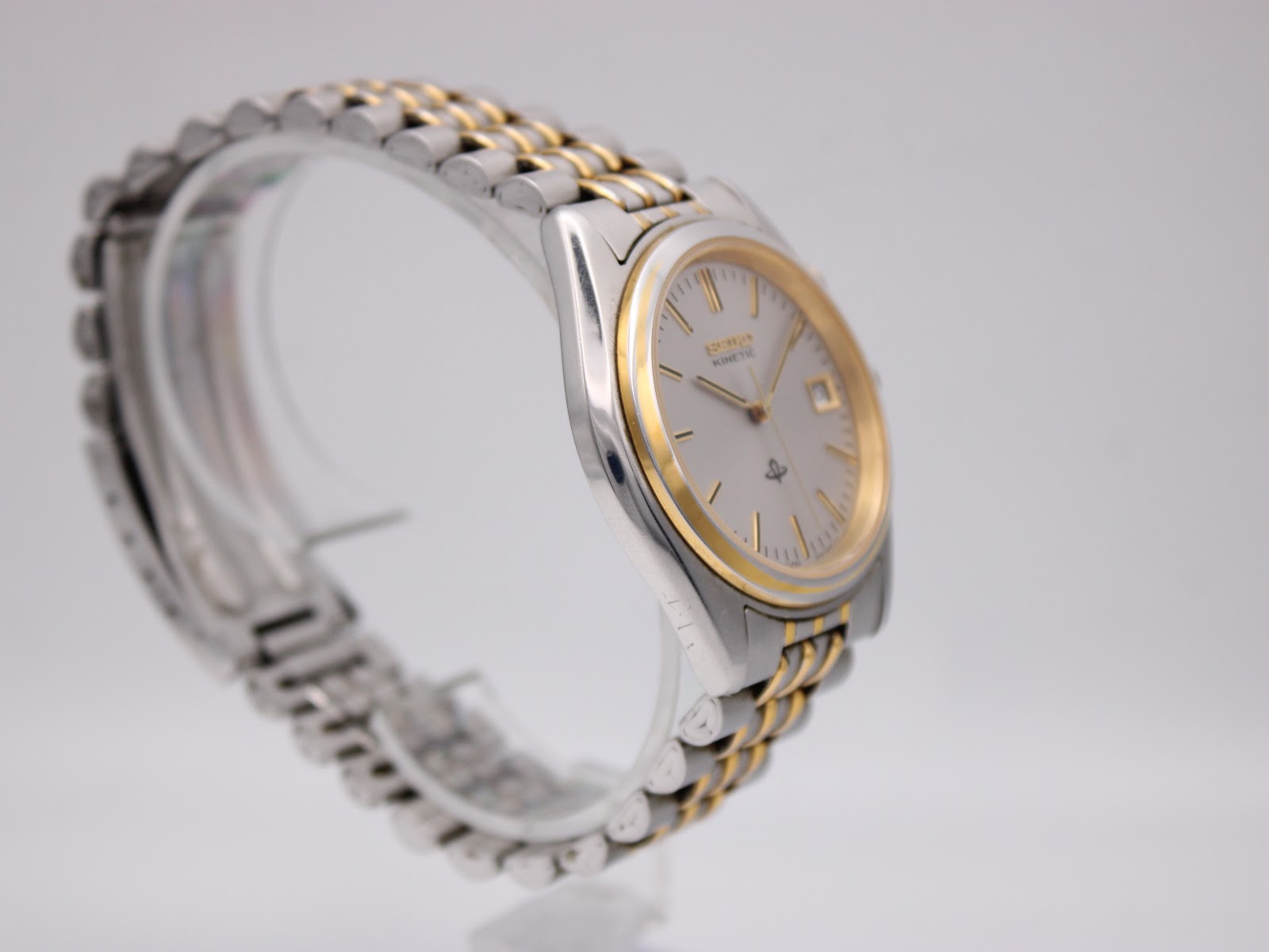 Left-side profile view of the Seiko Kinetic watch on a stand, highlighting the integrated two-tone bracelet and case design.