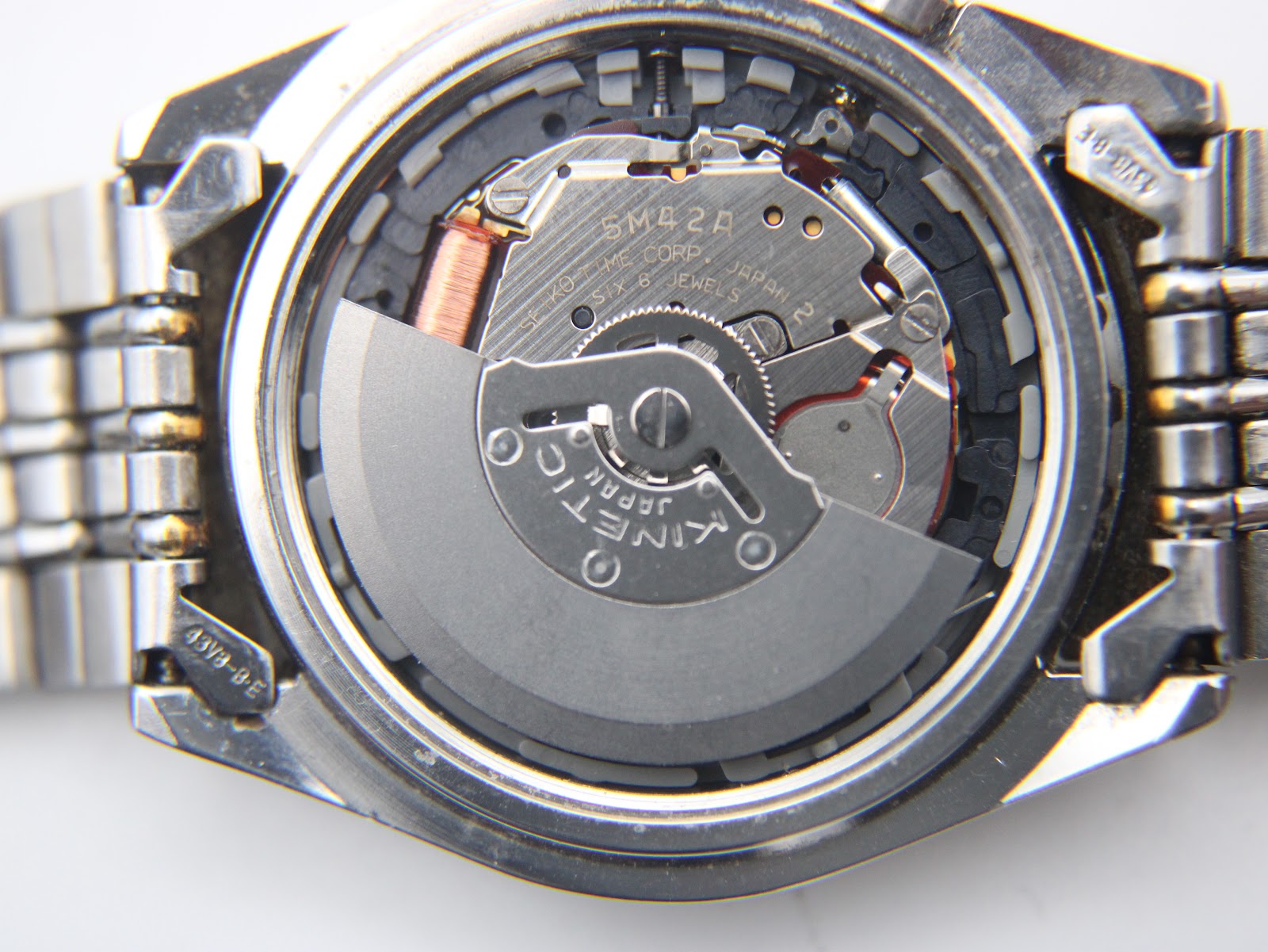 Close-up of the Seiko Kinetic 5M42A movement, revealing the oscillating weight, coil, and 'Japan 2 Jewels' engraving.