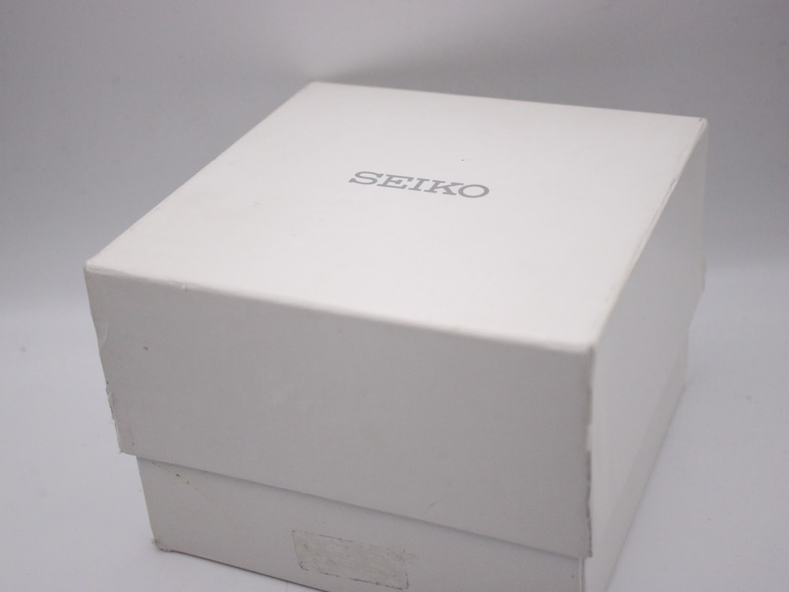 Top-down view of the white original Seiko watch box with the "SEIKO" logo printed on the lid.