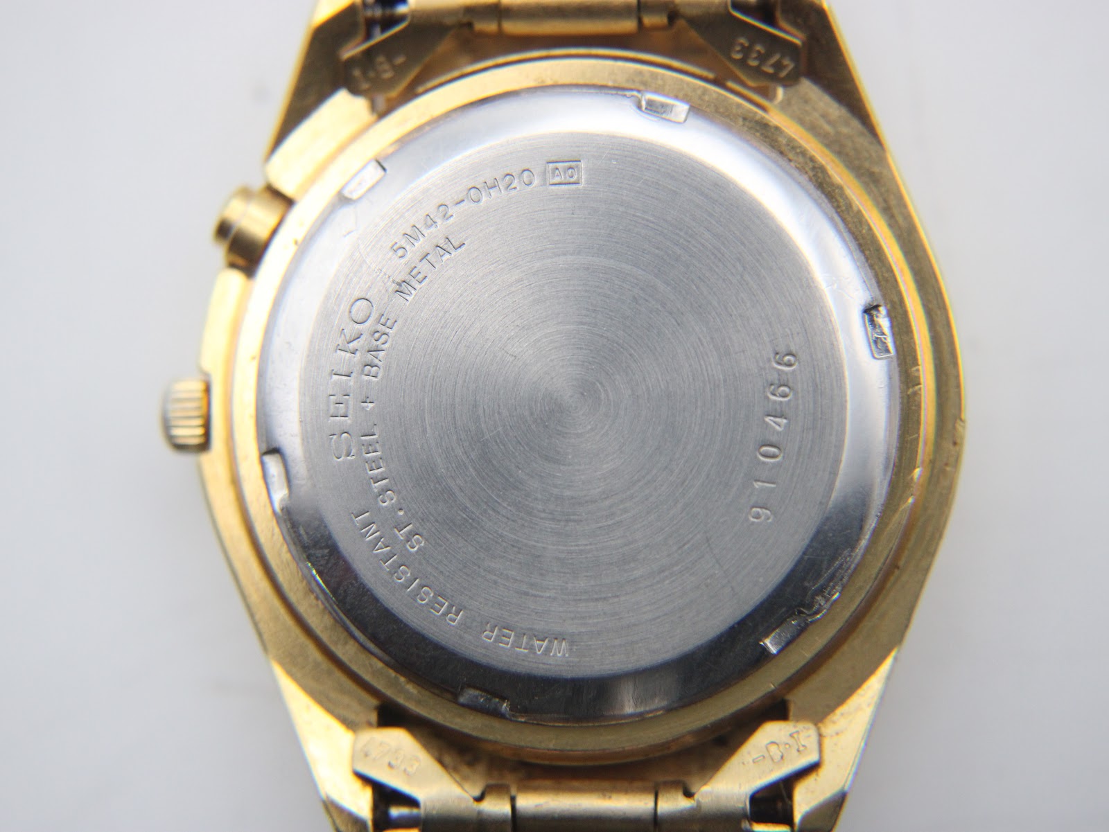 Close-up of the watch's stainless steel case back showing model number 5M42-0H20 and serial number 910466.