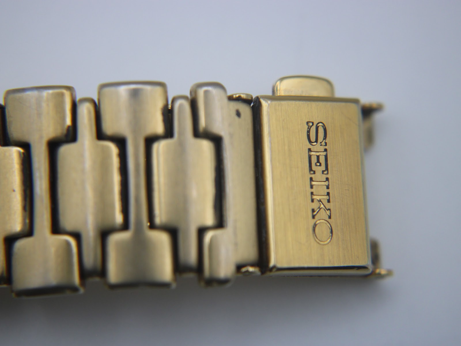 Close-up of the gold-toned bracelet clasp, clearly showing the "SEIKO" logo engraved on it.