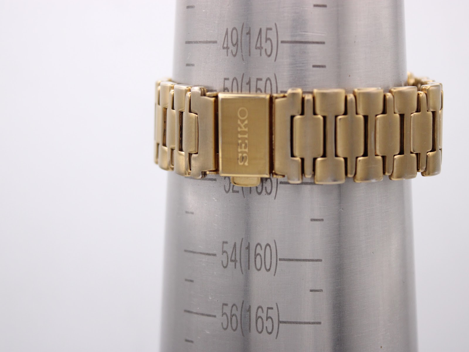 Close-up of the gold-toned bracelet on a wrist sizing mandrel, showing a circumference of approximately 165mm.