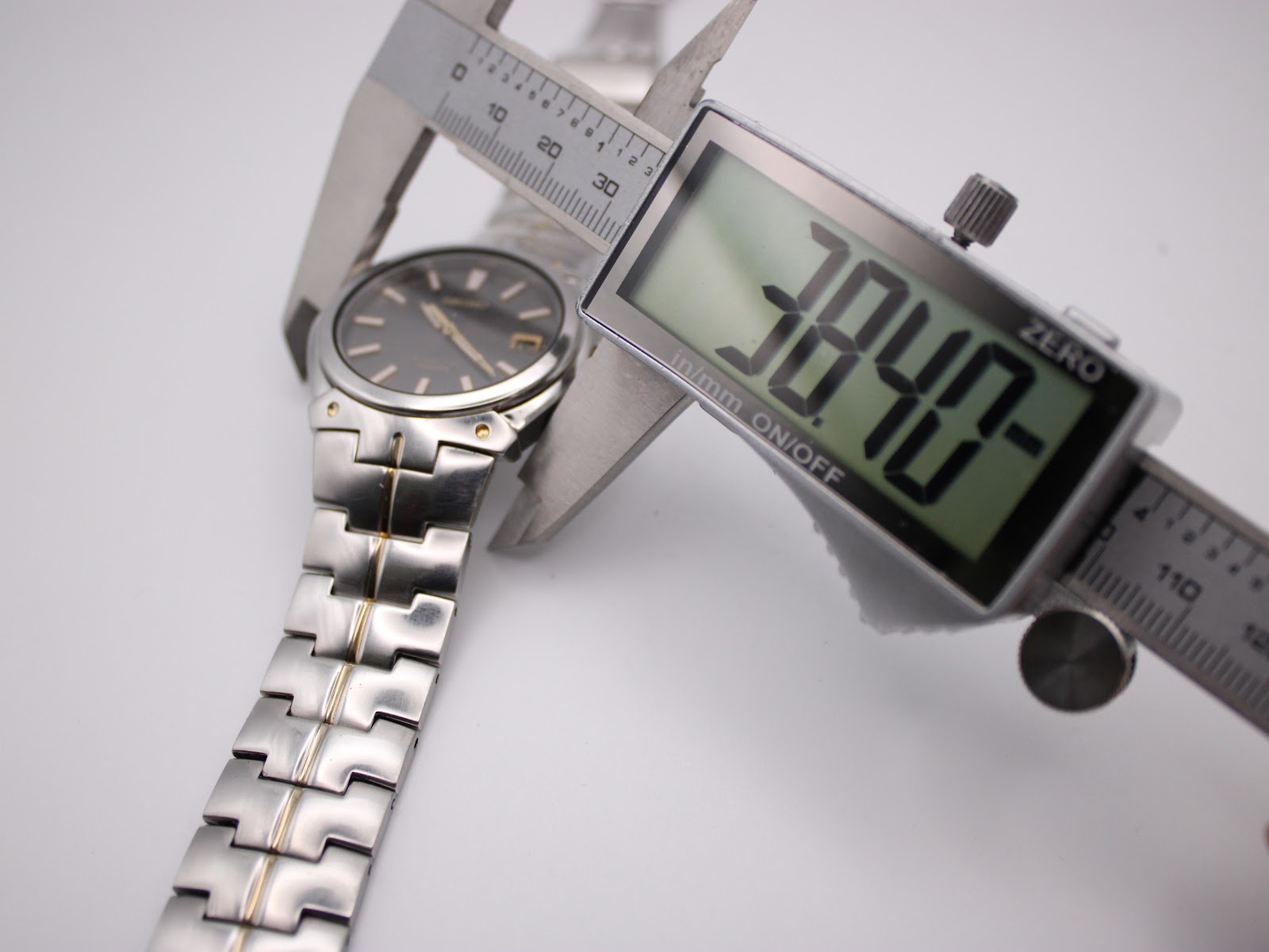 Digital caliper measuring the case diameter of the Seiko watch, showing 38.40mm on the display.