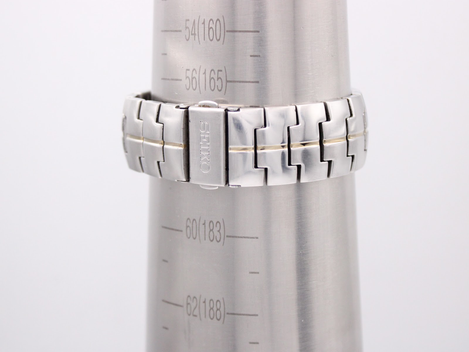 Rear view of the two-tone stainless steel bracelet on a wrist sizing gauge, showing the signed Seiko clasp.