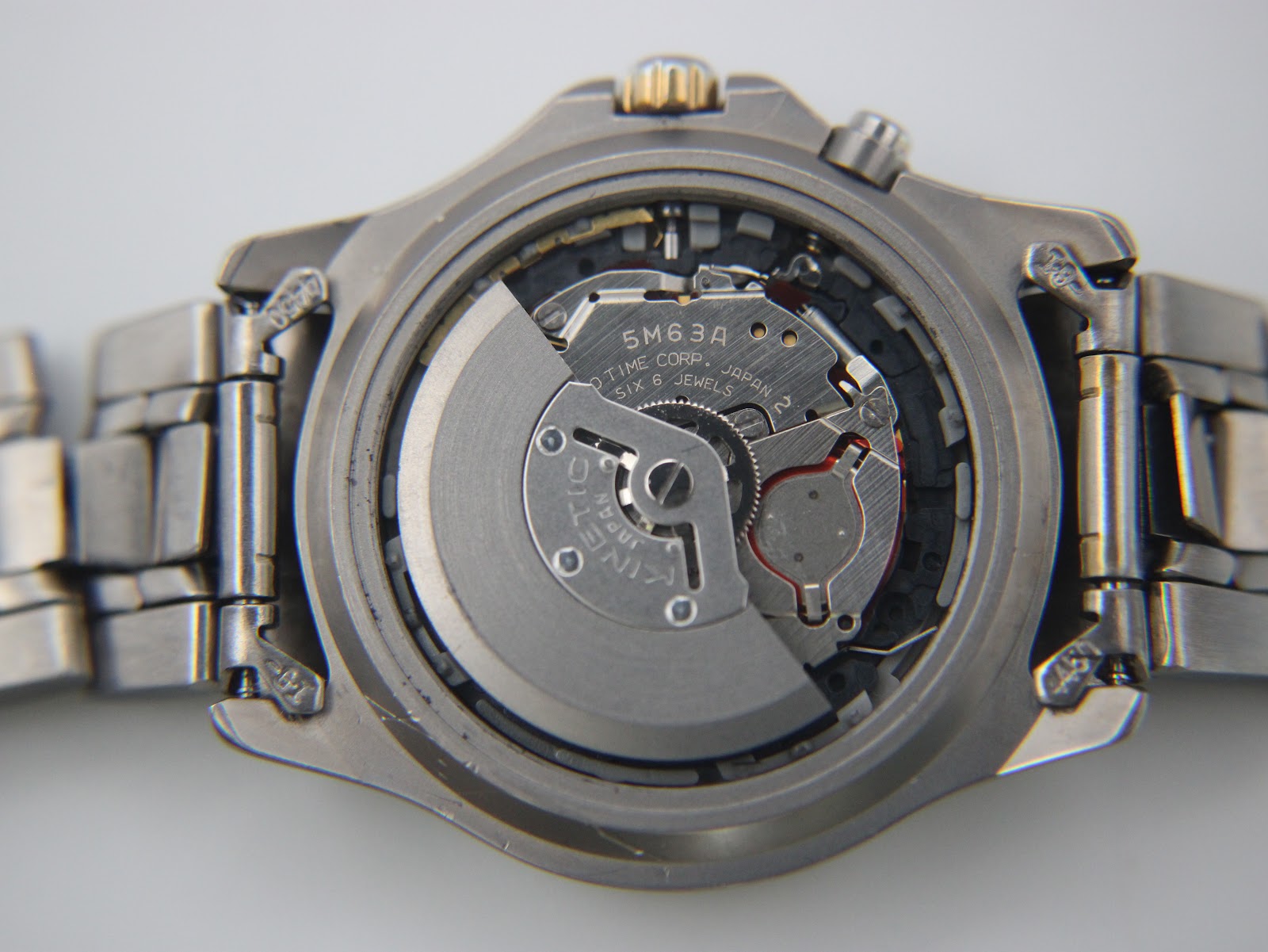 Detailed shot of the Seiko 5M63A Kinetic movement visible through the open case back, showing the oscillating rotor and gear train.