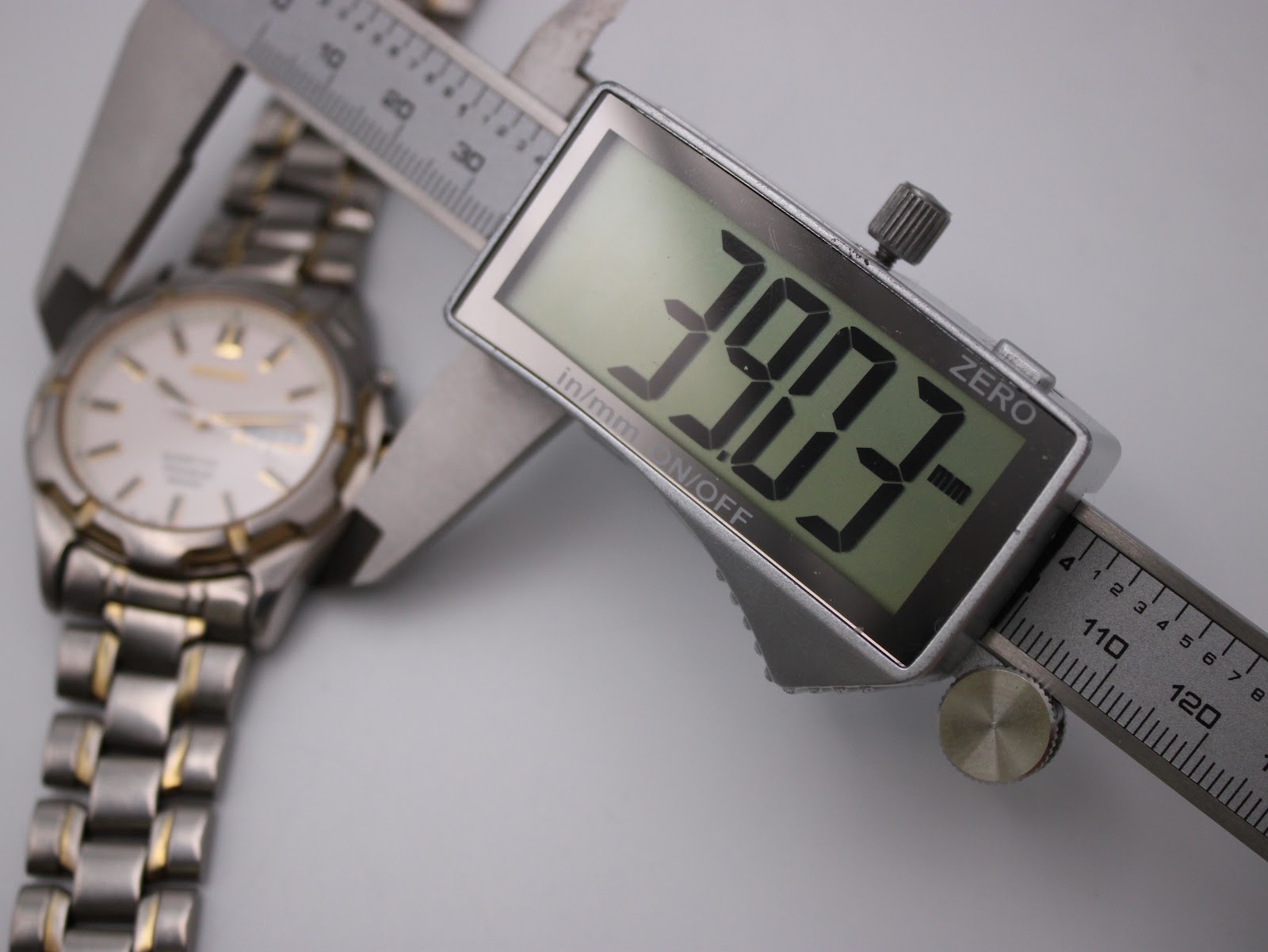 Digital caliper measuring the case diameter of the Seiko watch precisely, displaying a reading of 39.03mm.