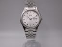 Front view of Seiko 7N43-9011 quartz watch with white dial and stainless steel jubilee bracelet on a clear stand.