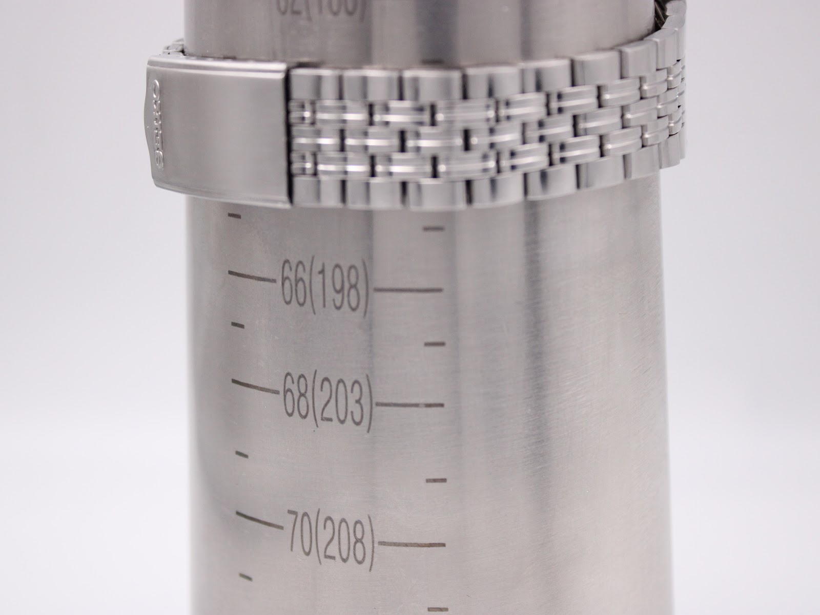 Close-up of the Seiko stainless steel jubilee bracelet clasp on a wrist sizing gauge, showing 198mm circumference.