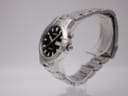 Angled right side view of the Seiko kinetic watch on a display stand, showing the crown and push-button.