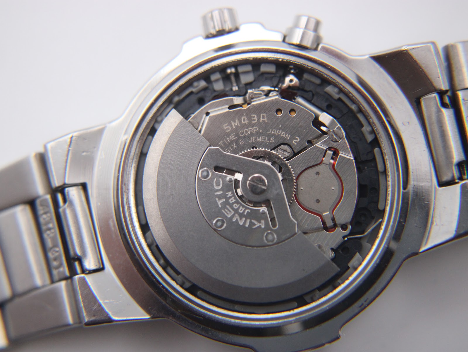 Macro shot of the Seiko 5M43A kinetic movement inside the watch, revealing 'TIME CORP. JAPAN 2' and '6 JEWELS'.