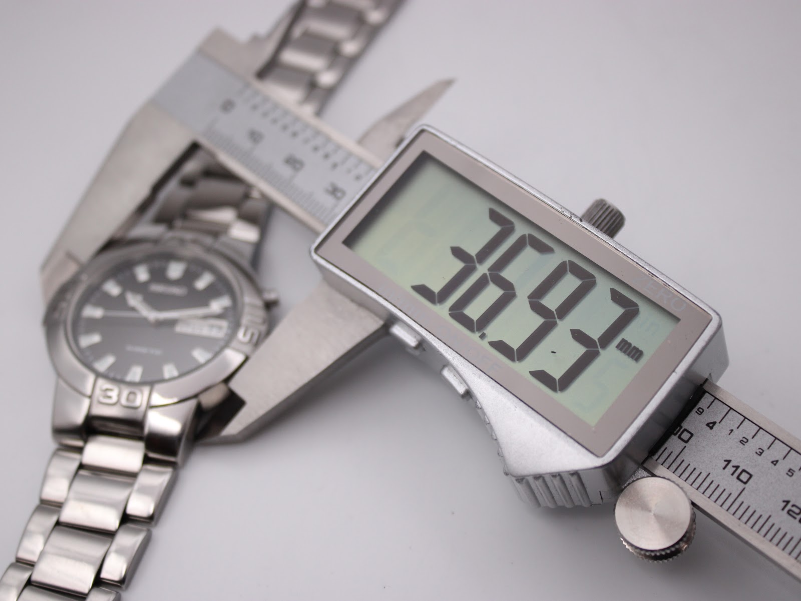 Digital caliper measuring the watch case diameter, displaying 36.93mm.