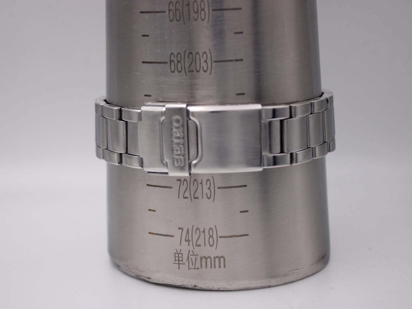 Watch bracelet with signed 'SEIKO' clasp on a wrist sizing gauge, indicating a circumference of approximately 213mm.
