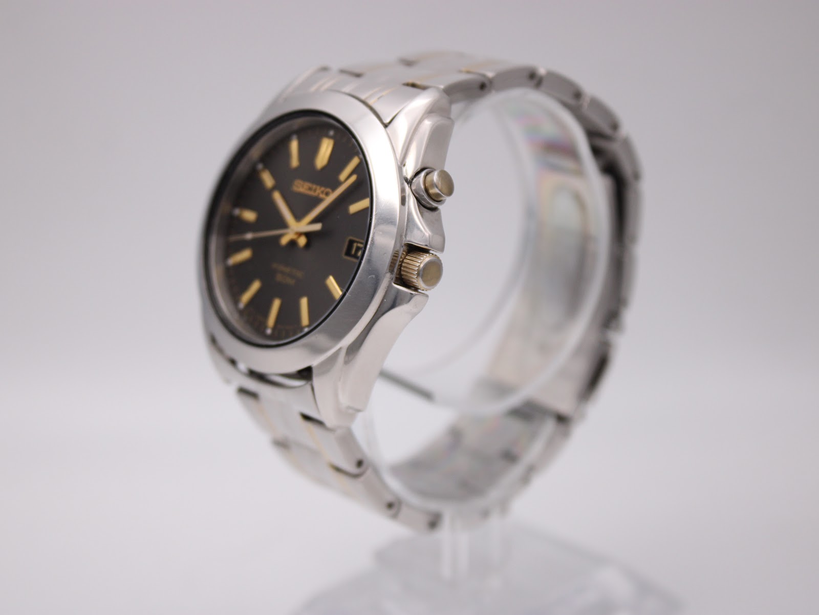 Angled side view of the Seiko kinetic watch on a display stand, showing the crown and case profile.
