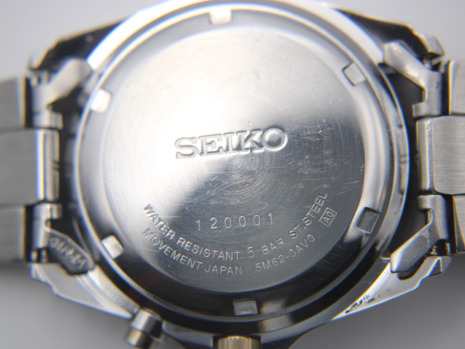 Close-up of the stainless steel case back, engraved with 'SEIKO', 'WATER RESISTANT 5 BAR', '5M62-0AV0', and serial '120001'.