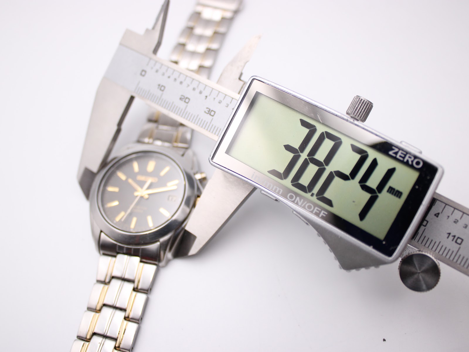 Digital caliper measuring the case diameter of the Seiko watch, showing a reading of 38.24mm.