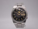 Front view of the Seiko 7009-3130 automatic watch with black dial, gold baton indices, and stainless steel bracelet.