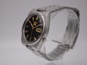 Angled side view of the Seiko 7009-3130 watch showing the stainless steel case and bracelet on a display stand.
