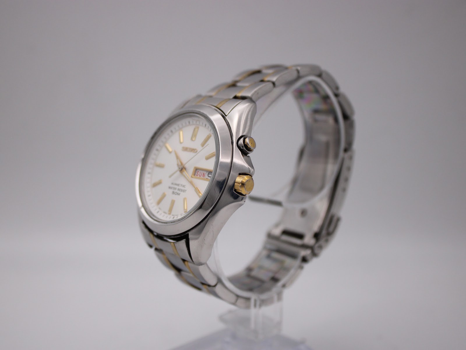 Angled side view of the Seiko kinetic watch showing case profile and gold-tone crown.
