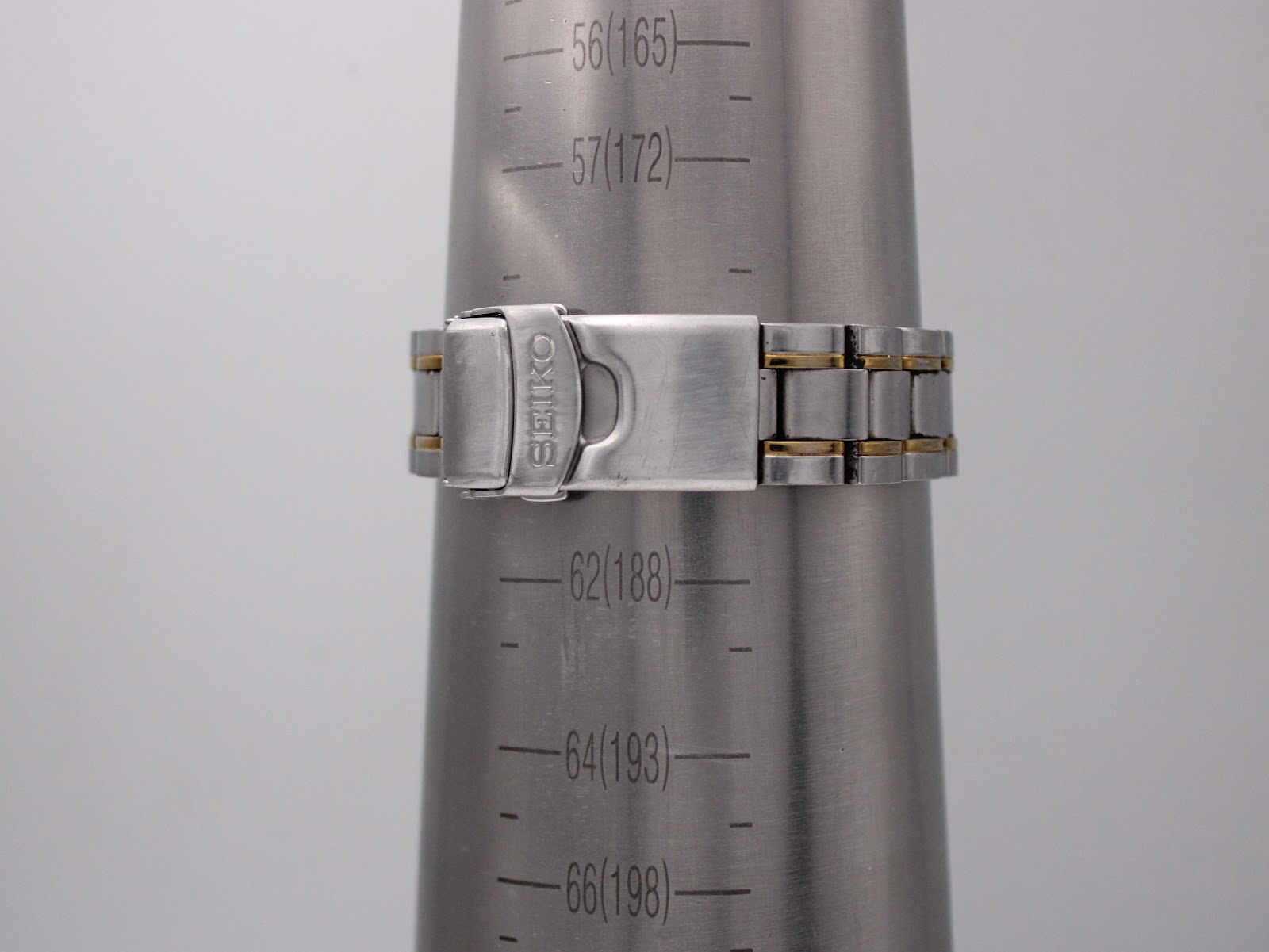 Seiko two-tone bracelet clasp closed on a wrist sizing gauge, showing 188mm circumference.