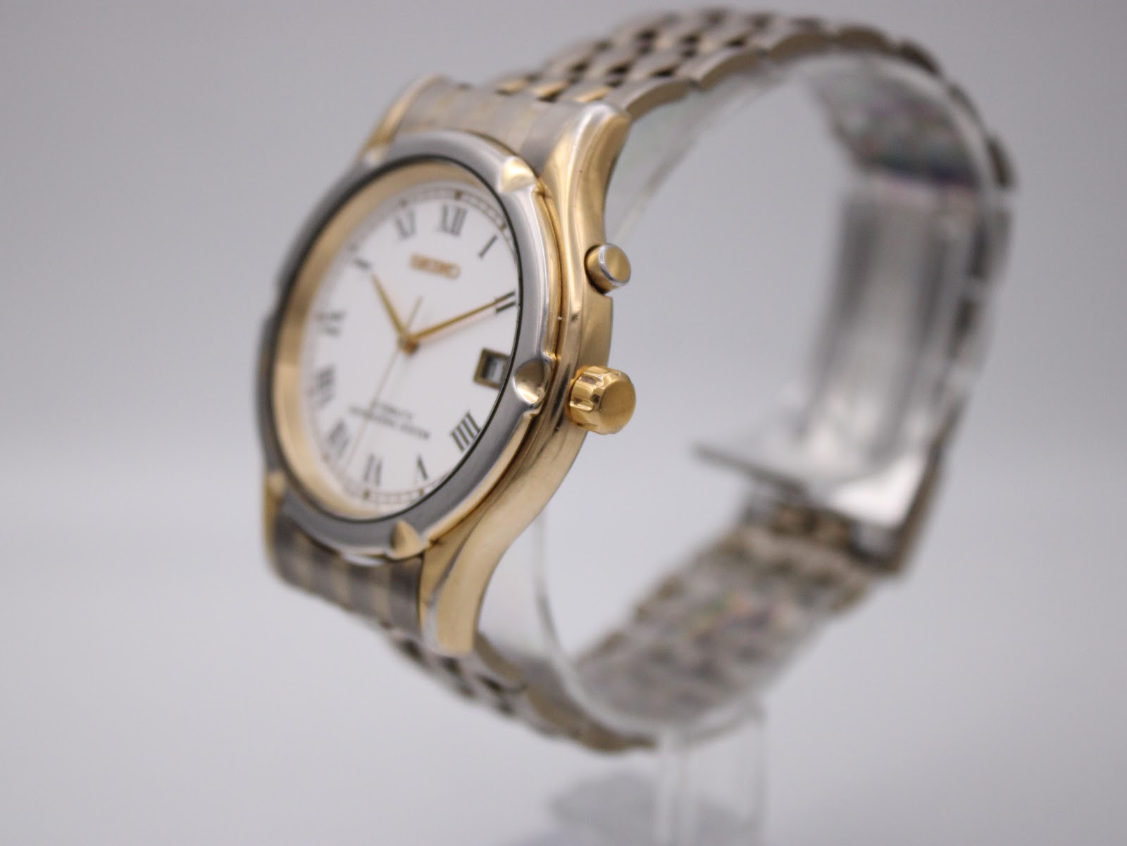 Angled view of the Seiko watch, showing the gold-plated crown and pusher on the right side of the two-tone case.