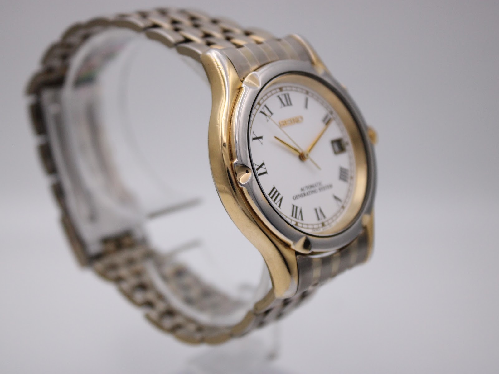 Another angled view of the Seiko watch, highlighting the contrasting gold and silver tones of the case and integrated bracelet.